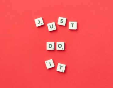 Motivational phrase 'Just Do It' spelled with Scrabble letters on a red background.